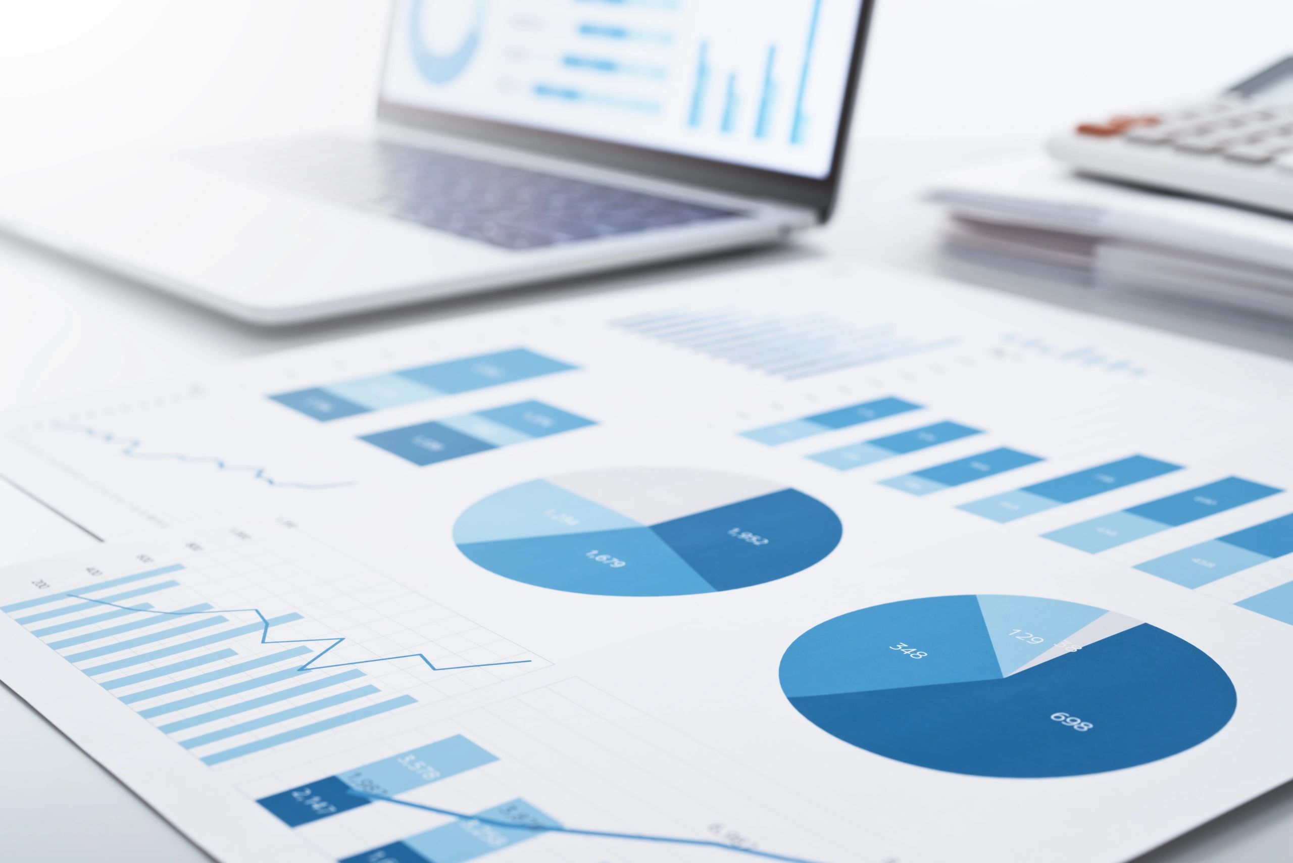 Business reports and charts on a laptop